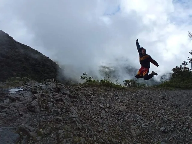 Eine Person springt hoch in die Luft auf einem felsigen Bergpfad.